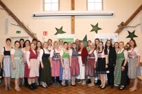 Gruppe von Frauen im Dirndl und ein Mann stehen vor einer mit Sternen geschmückten Wand
