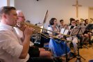 Eine Blaskapelle sitzt in einem Raum und spielt Musik.