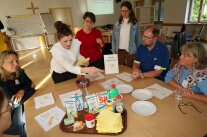 Gruppe von 7 Personen sitzt an Tisch mit Reinigungsmitteln