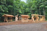 Holzbauten mit Sitzgelegenheiten und einer Tafel auf einer Waldlichtung