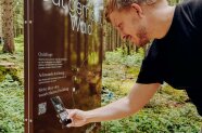 Ein Mann scannt mit seinem Smartphone den QR-Code auf einer Infotafel