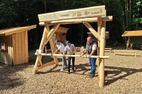 Drei Männer sägen einen Baumstamm am Eingang zum Naturklassenzimmer durch