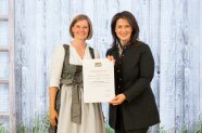 2 Frauen stehen nebeneinander und halten Urkunde