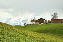 Ein Hof vor Alpenkulisse, auf dem ein Kran steht